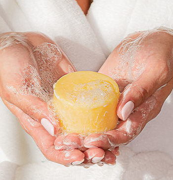 Manos sosteniendo barra de shampoo sólido cosatica