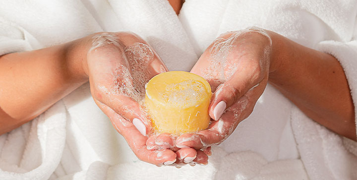 Manos sosteniendo barra de shampoo sólido cosatica